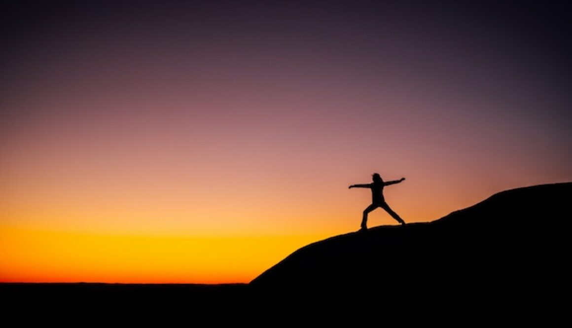 Woman Stretching as the sun sets on a hill