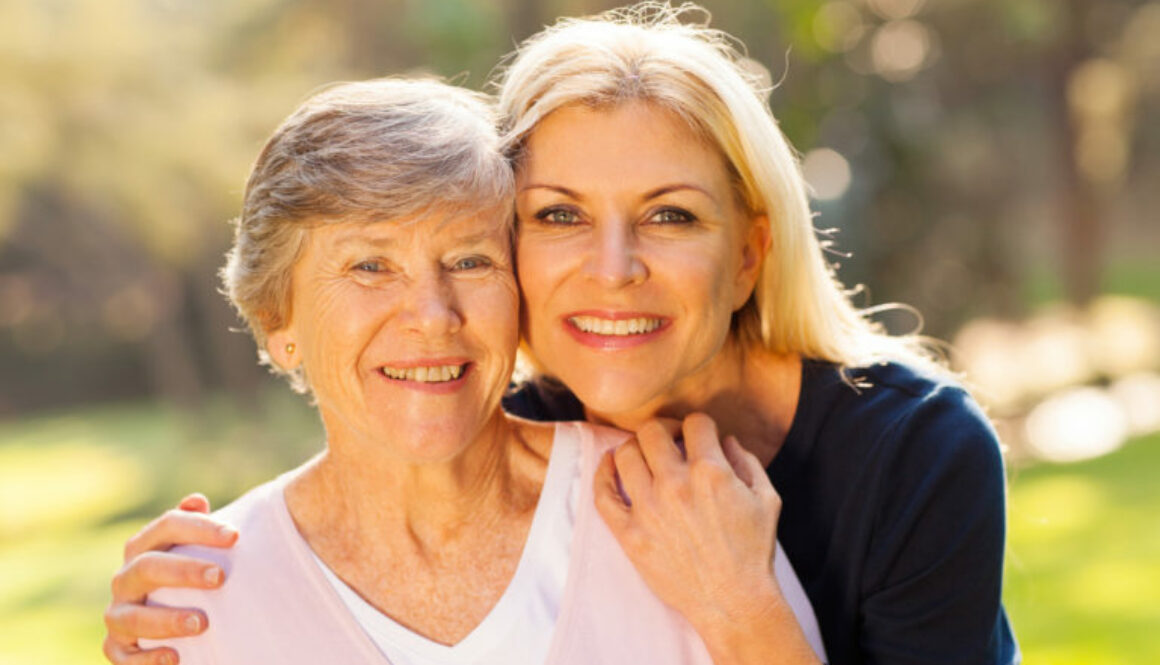 smiling senior woman and middle aged daughter outdoors