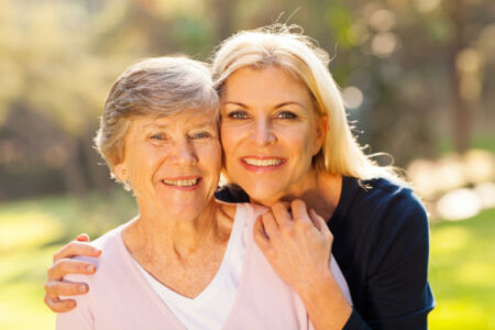 smiling senior woman and middle aged daughter outdoors