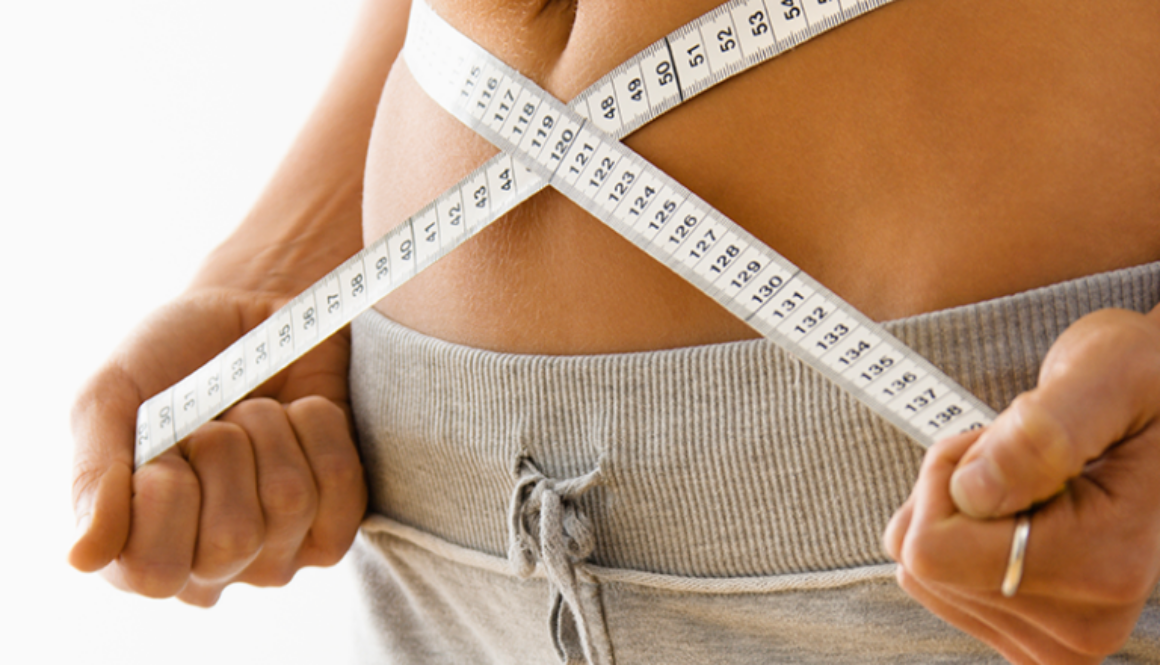 Woman holding a measuring tape around her waist