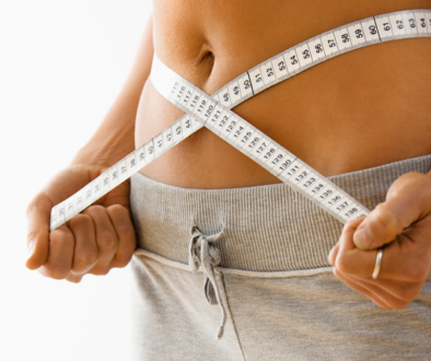 Woman holding a measuring tape around her waist