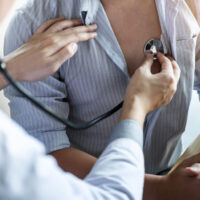 Doctor using a stethoscope checking patient with examining