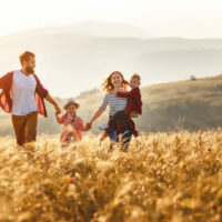 Happy family walking in the fields at sunset