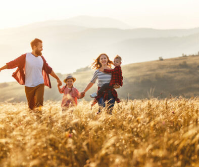 Happy family walking in the fields at sunset
