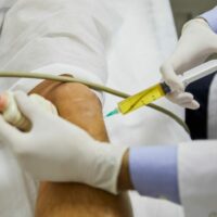 Doctor injecting patient in knee with Stem Cell Therapy