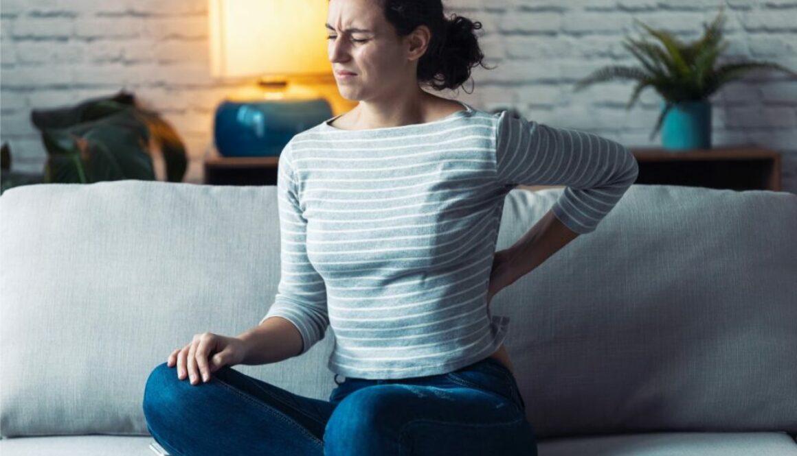 Woman with lower back pain sitting on sofa