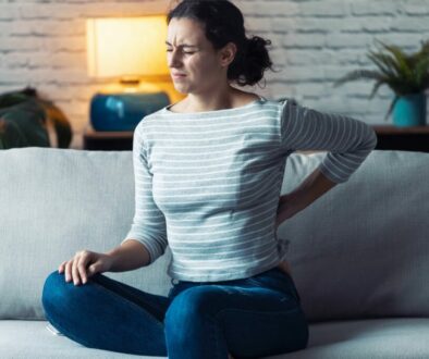 Woman with lower back pain sitting on sofa