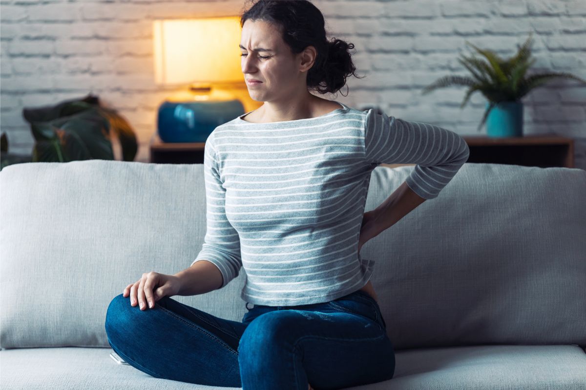 Woman with lower back pain sitting on sofa