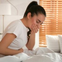 Woman with Leaky Gut Syndrome holding stomach in bed