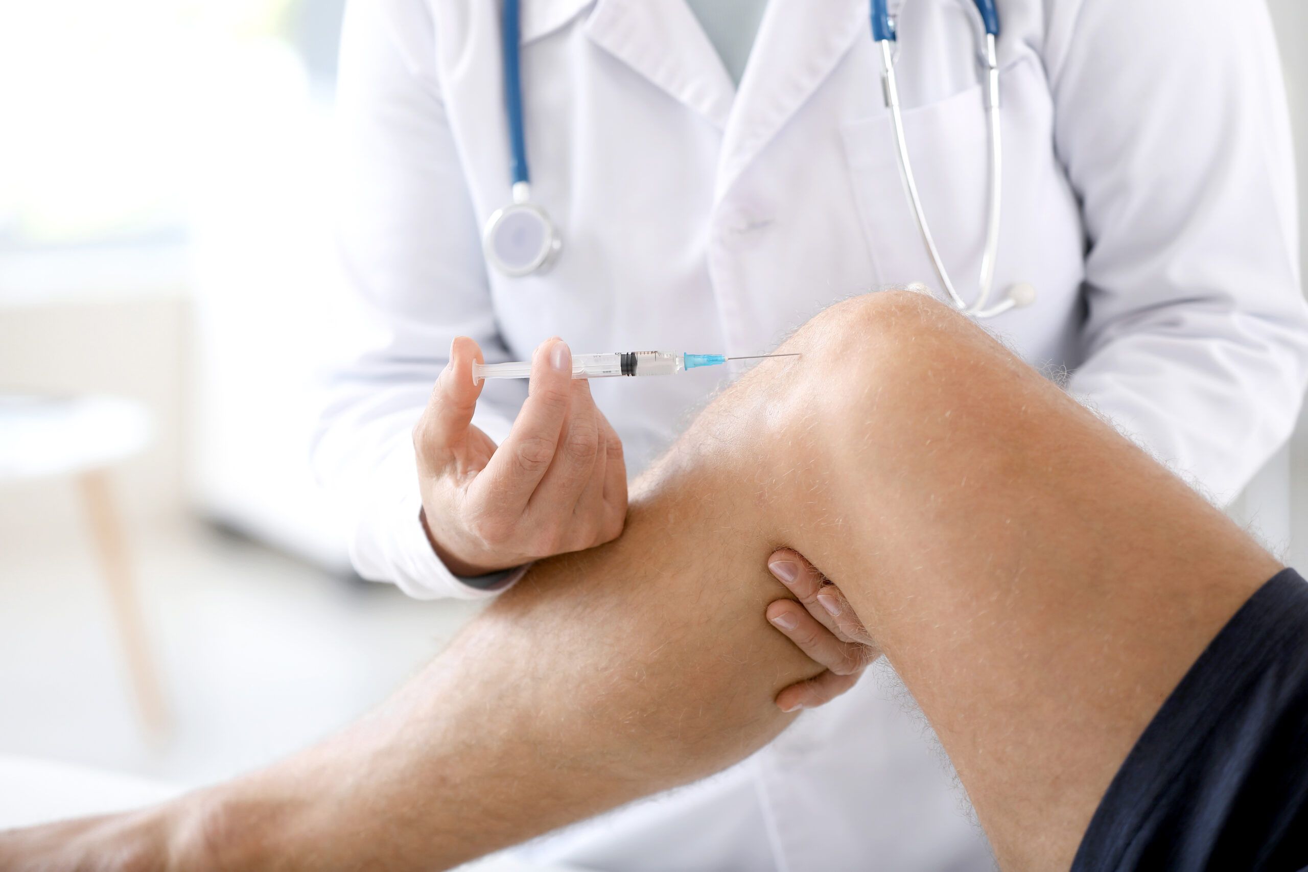 Doctor giving hyaluronic gel injection for knee pain