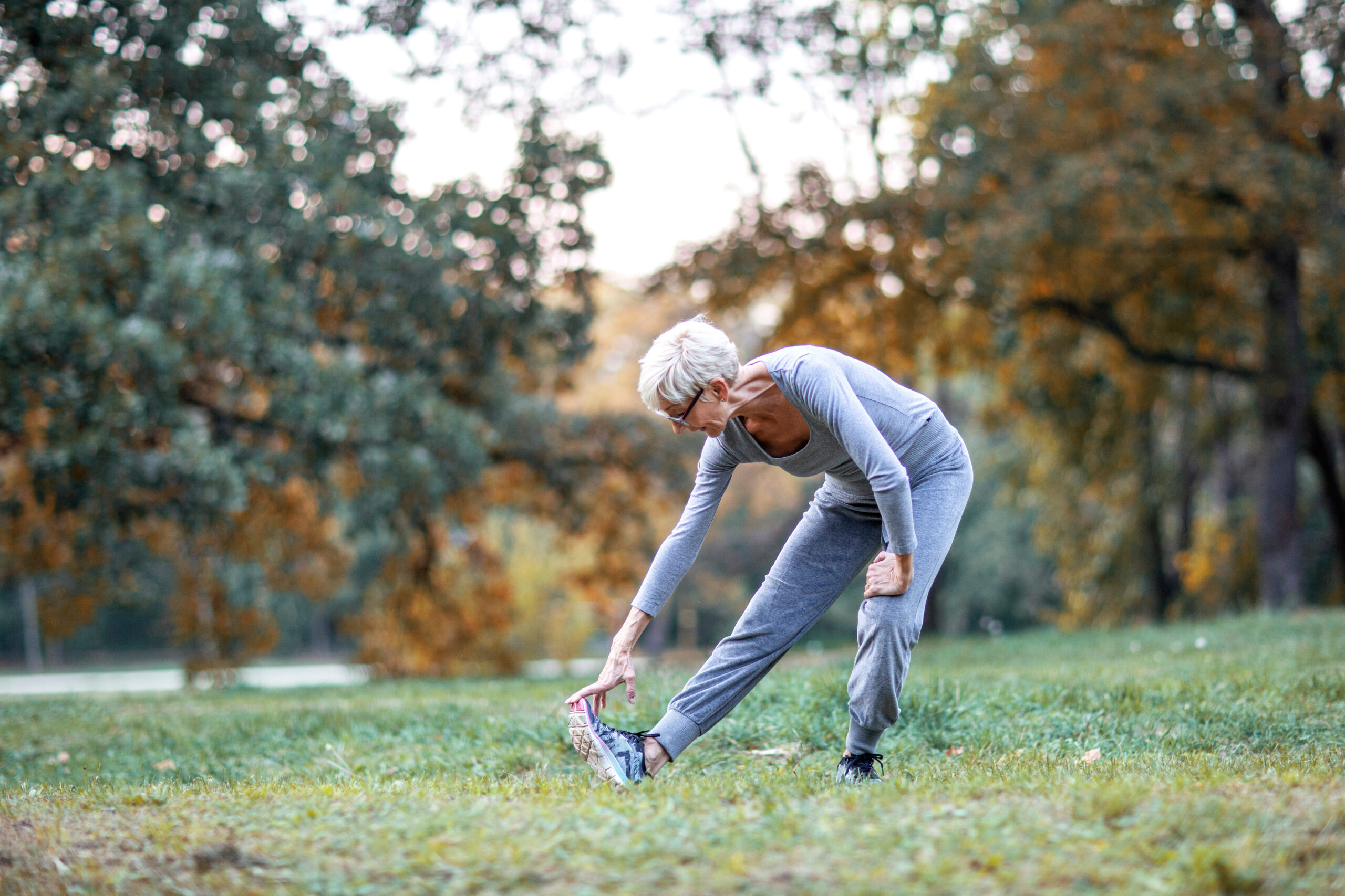 Older woman bending knee to touch toes