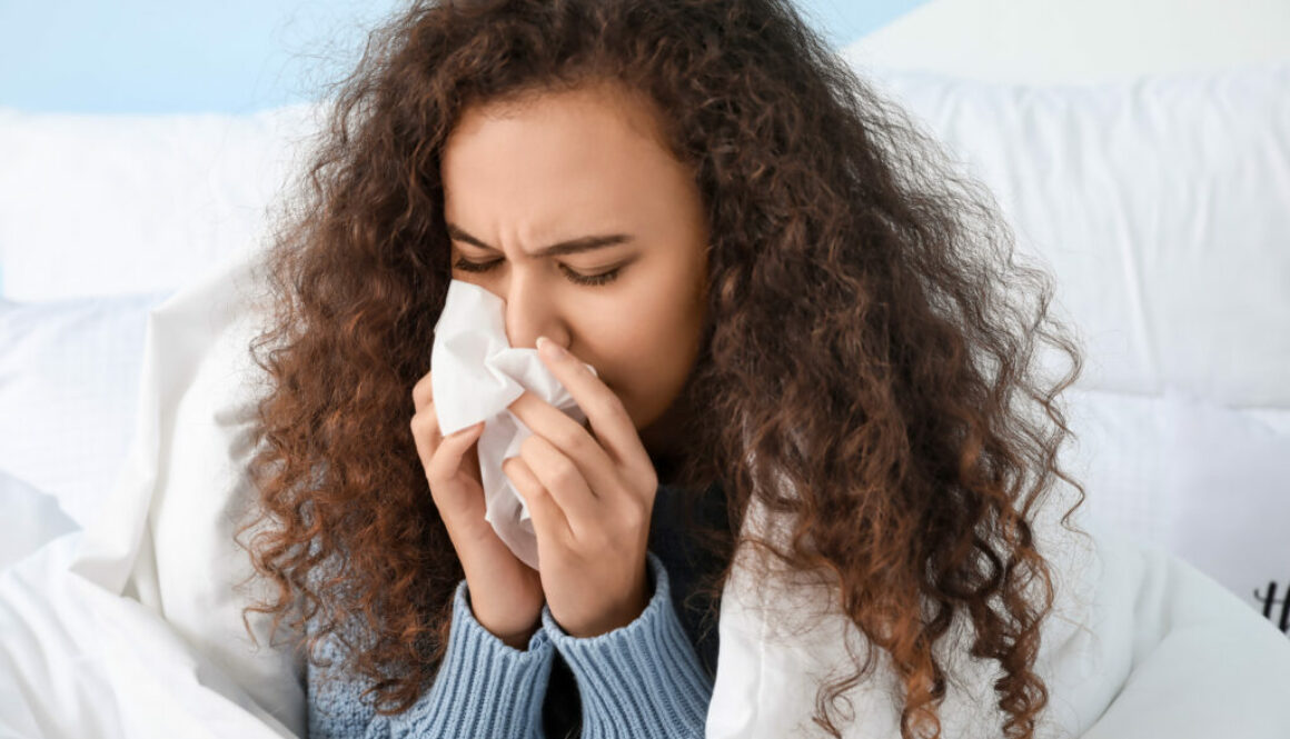 Someone sneezing into a Kleenex tissue what suffering from Covid or flu related symptoms.
